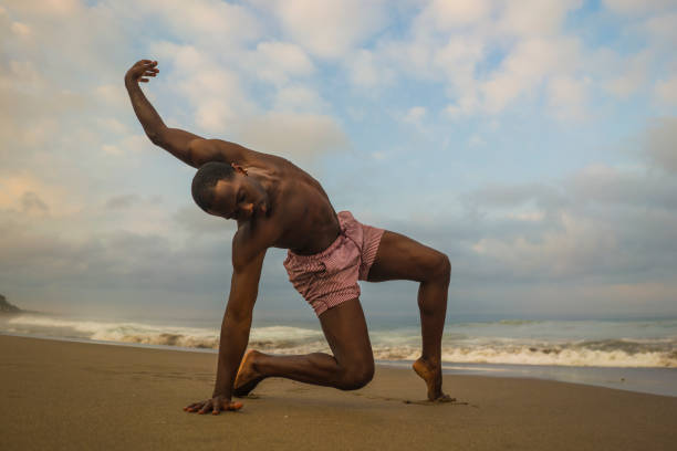 contemporary dance choreographer and dancer doing ballet beach workout . a young attractive and athletic black African American man dancing on sunrise doing dramatic performance contemporary dance choreographer and dancer doing ballet beach workout . a young attractive and athletic black African American man dancing on sunrise doing dramatic performance contemporary dance stock pictures, royalty-free photos & images