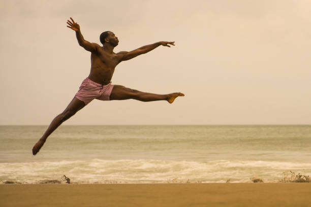 istock dramatic contemporary dance choreographer doing ballet beach workout . young attractive and athletic black African American man dancing on sunrise jumping elegant and with amazing plasticity 1168701249