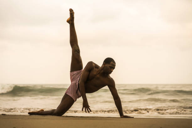 istock contemporary dance choreographer and dancer doing ballet beach workout . a young attractive and athletic black African American man dancing on sunrise doing dramatic performance 1168701300