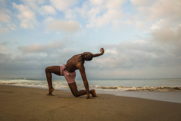 contemporary dance choreographer and dancer doing ballet beach workout . a young attractive and athletic black African American man dancing on sunrise doing dramatic performance contemporary dance choreographer and dancer doing ballet beach workout . a young attractive and athletic black African American man dancing on sunrise doing dramatic performance contemporary dance stock pictures, royalty-free photos & images