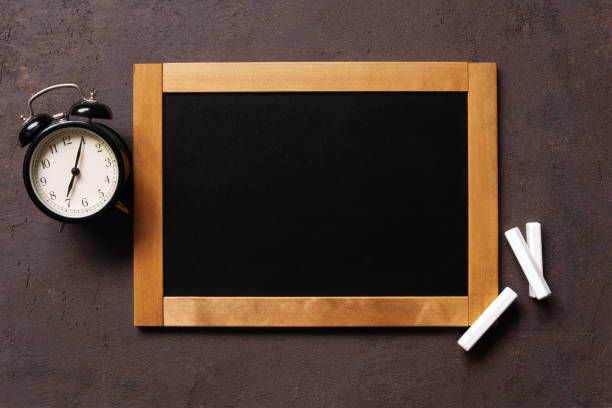 Vintage chalkboard and alarm clock on the textured brown surface, top view and copy space