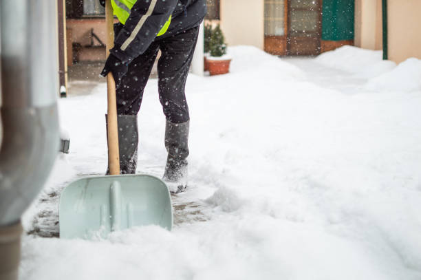 mann mit schneeschaufel reinigt gehweg - winterdienst stock-fotos und bilder