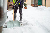 Man with snow shovel cleans sidewalk