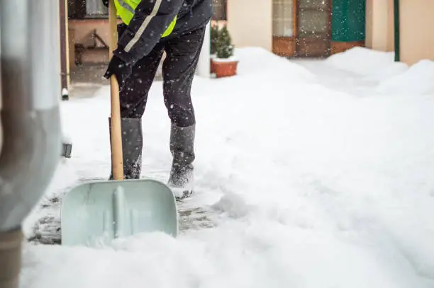 Photo of Man with snow shovel cleans sidewalk