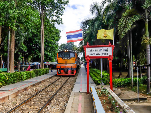 treno in arrivo alla stazione ferroviaria del fiume kwai a kanchanaburi, thailandia. - kwai river kanchanaburi province bridge thailand foto e immagini stock