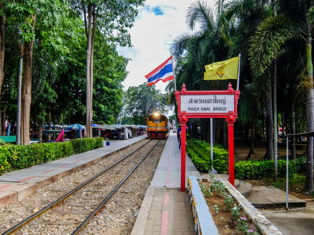 train coming to river kwai train station in kanchanaburi, thailand. - kwai river kanchanaburi province bridge thailand imagens e fotografias de stock