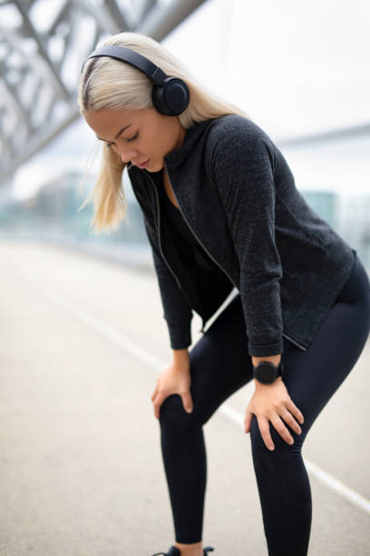 wyczerpana kobieta biegacz odpoczywa z rękami na kolanach po treningu - hand on knee audio zdjęcia i obrazy z banku zdjęć
