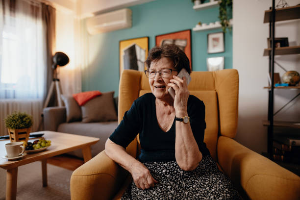 retrato de mujer senior en casa usando teléfono móvil y tecnologías - one old woman only fotografías e imágenes de stock