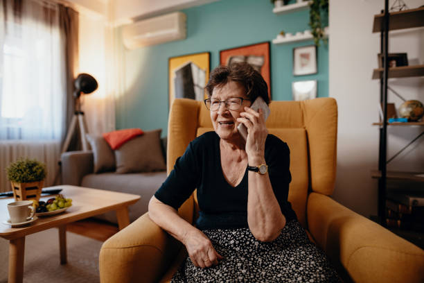 Portrait of senior woman at home using mobile phone and technologies stock photo