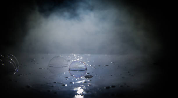 istock Rainbow soap bubbles on a dark background. Abstract wet surface with fog and light 1168728203
