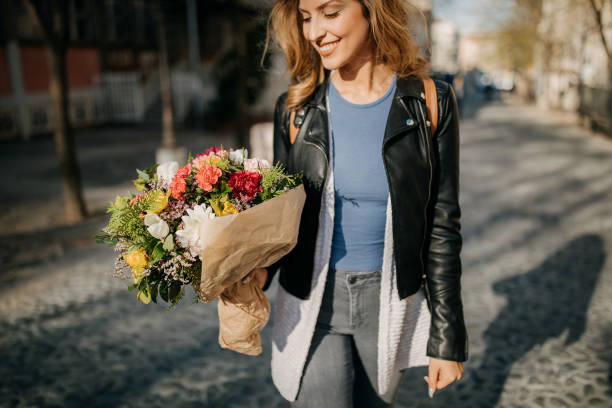 istock Young woman walking with flower bouquet in hands 1168728791