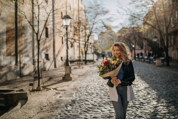 istock Young woman walking with flower bouquet in hands 1168729462