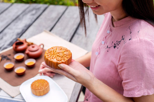 nahaufnahme der asiatischen frau hält leckeren mondkuchen mit chinesischem tee auf dem tisch gesetzt, feiern mond kuchen festival - food and drink holidays and celebrations isolated objects birthdays stock-fotos und bilder