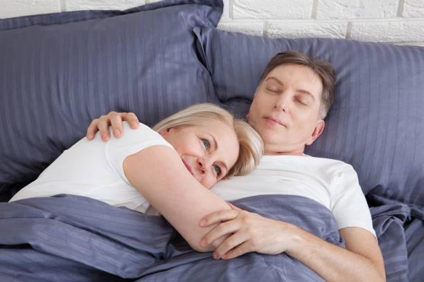 couples calmes dormant et cuillerant dans le lit dans la chambre à coucher à la maison. - spooning photos et images de collection