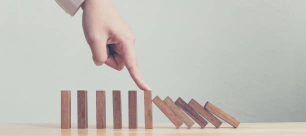 arresto a mano dell'effetto di crisi aziendale domino in legno o del concetto di protezione del rischio - debt crisis foto e immagini stock