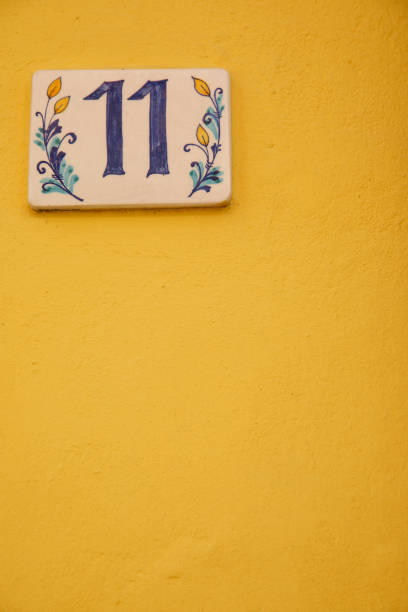 istock Number 11 street address tile on old wall. 1168742832