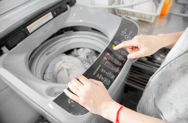 femme dans la buanderie lavez des vêtements avec la machine à laver. femme au foyer heureuse - sweat women wet shirt photos et images de collection