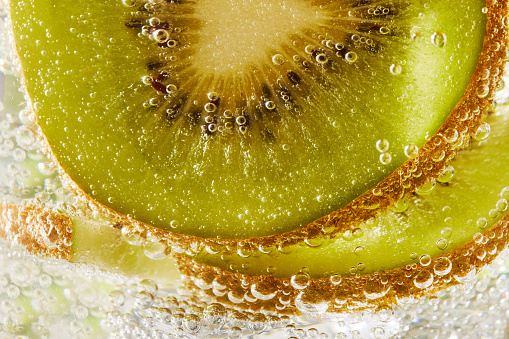 Close up of water with kiwi slices and bubbles