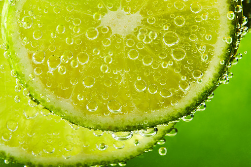 Close up of water with lime slices and bubbles