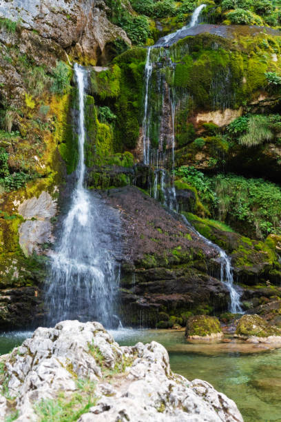 istock Beautiful emerald color waterfall flowing over stones covered in moss 1168745814