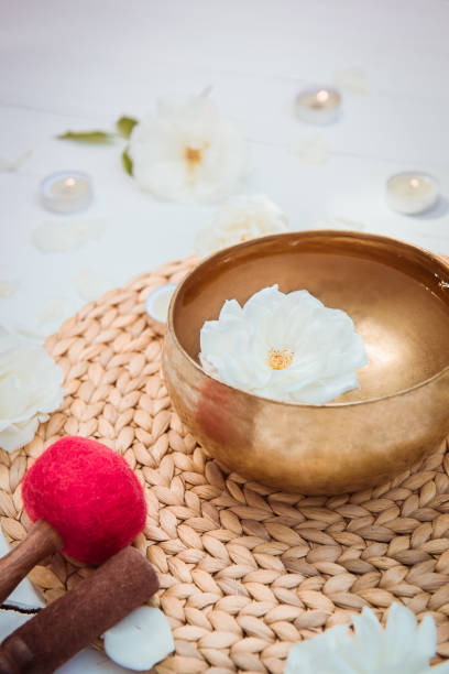 istock Tibetan singing bowl with floating in water rose inside. Special sticks, burning candles, flowers petals on the white wooden background. Meditation and Relax. Exotic massage. Vertical card. Copy space 1168747437