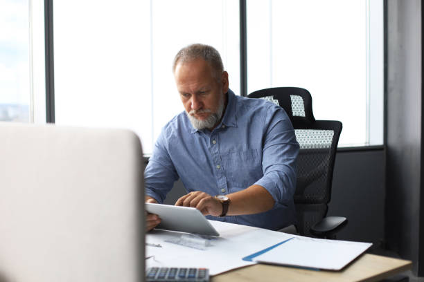 istock Mature businessman working using digital tablet while sitting in the modern office. 1168752202