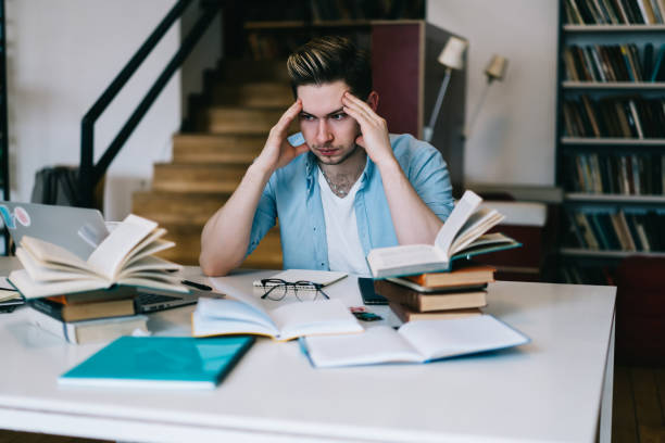 Tired hipster guy feeling headache while preparing for examination in college worried about results learning in campus,unhappy overworked male nervous about deadlines doing project in coworking space el tipo hipster cansado siente dolor de cabeza mientras se prepara para el examen en la universidad preocupado por el aprendizaje de resultados en el campus, infeliz sobrecargado de trabajo nervioso masculino acerca de los plazos haciendo proyecto en el es