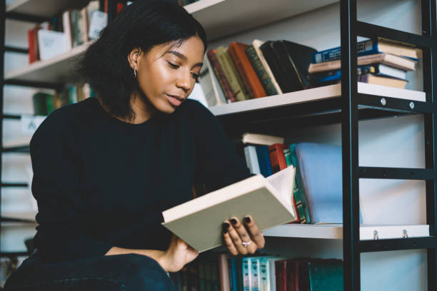 istock Serious female dark skinned student concentrate on reading book in college library, young african american woman booklover enjoying interesting novel on leisure, back female model choosing literature 1168752391