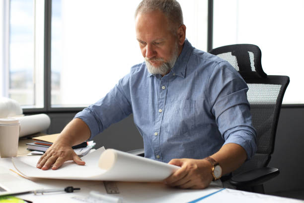 istock Handsome mature business man using blueprint while working in the modern working space. 1168752409