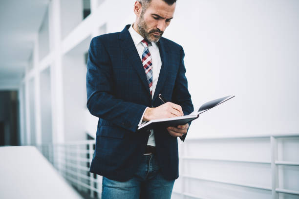 istock Pensive mature proud ceo dressed in formal wear writing down records in notepad developing business strategy.Concentrated businessman 50 years old signing financial documents of corporate company 1168752677