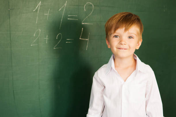 istock The boy solved arithmetic equations at school. A child writes on the blackboard. Schoolboy about a board solves examples. Back to school concept. 1168754474