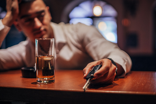 One drunk man sitting at bar counter, holding car keys.