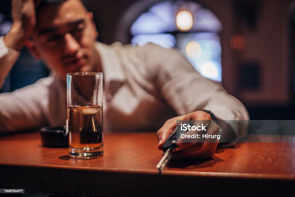 Drunk man holding car keys One drunk man sitting at bar counter, holding car keys. Drunk Driving Stock Photo
