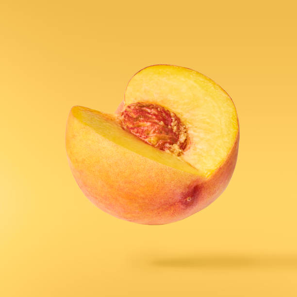 Flying fresh ripe peach with green leaves isolated stock photo