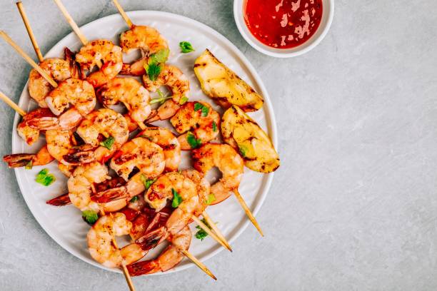 sweet chilli shrimp skewers with lemon and parsley on gray stone background - shrimp imagens e fotografias de stock