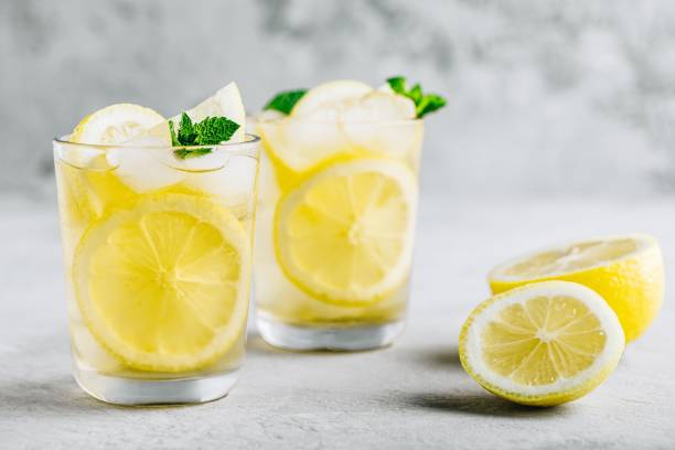 istock Lemonade with lemon, mint and ice cubes in glass on gray stone background. 1168757487