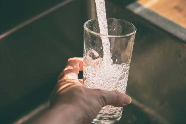 Fresh water Female pouring fresh drinking tap water into the glass. Close-up on hand holding glass. purified water photos stock pictures, royalty-free photos & images
