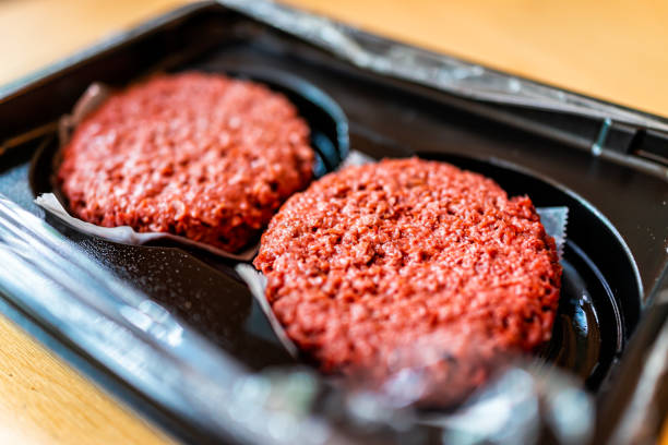 primer plano de dos hamburguesas de hamburguesa de carne vegana roja cruda sin cocinar en envases de plástico - hamburguesa vegetariana fotografías e imágenes de stock