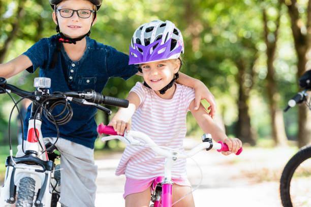Brother And Sister Riding Bikes In Park