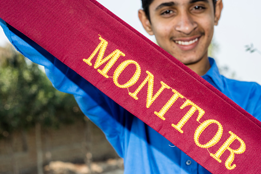 a teenager school boy is feeling proud and showing monitor batch