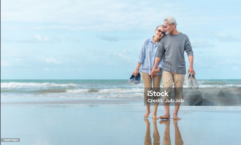 Age, Voyage, Tourisme et concept de personnes - couples aînés heureux retenant des mains et marchant sur la plage d'été - Photo de Troisième âge libre de droits