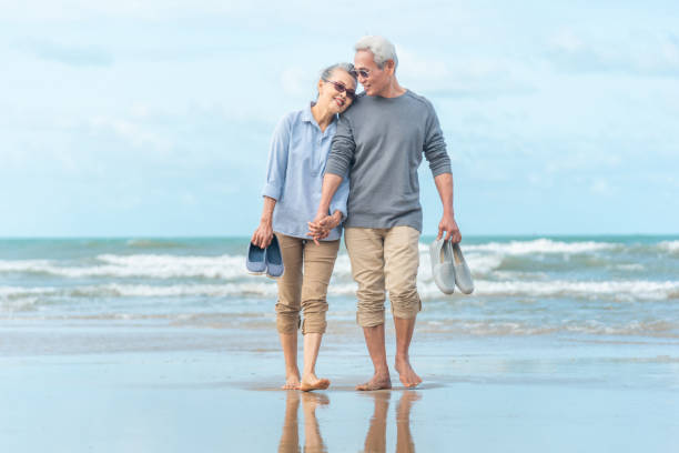 istock Senior asian Couple Running Along Winter Beach 1168771667