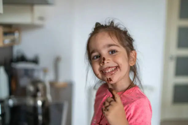 Photo of Child eating chocolate with her finger