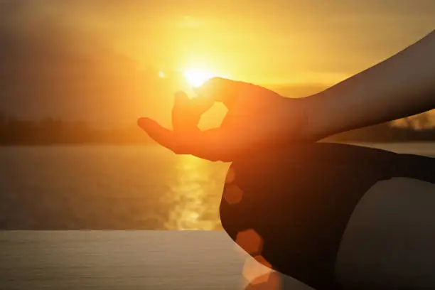 Photo of Young women meditate while doing yoga meditation, spiritual mental health practice with silhouette of lotus pose having peaceful mind relaxation on beach outdoor with sunset golden heavenly.