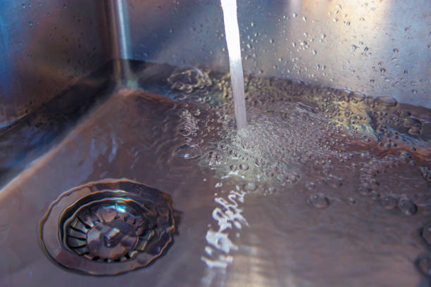 Water flows from the faucet into the sink. Filling the sink with water, preparation for the hand wash dishes