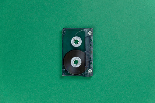 transparent audio cassette tape on a green background. retro music magnetic technology