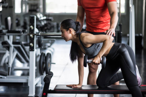 istock trainer coach dumbbell exercise to woman 1168777725