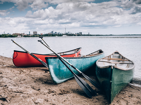 City panorama of downtown Toronto, view off the Lake Ontario. Wooden canoes pared on the shore in the foreground.