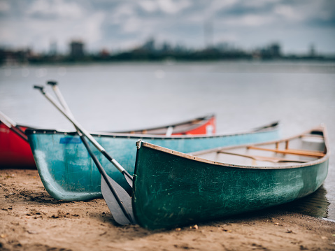 City panorama of downtown Toronto, view off the Lake Ontario. Wooden canoes pared on the shore in the foreground. Selective focus achieved with tilt and shift lens, applying maximum amount of tilt.