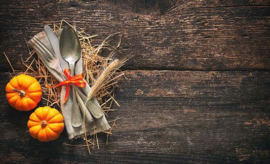 Autumn background from pumpkins and wheat with vintage place setting on old wooden table. Thanksgiving day concept